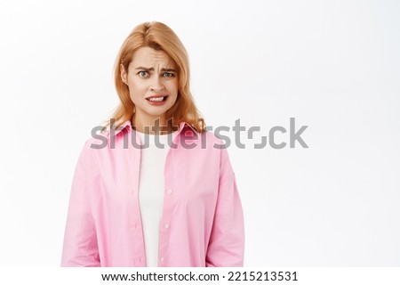 Yikes, thats awful. Young woman grimaces from cringe and disgusting emotion, looking with aversion at camera, dislike face, standing over white background Royalty-Free Stock Photo #2215213531