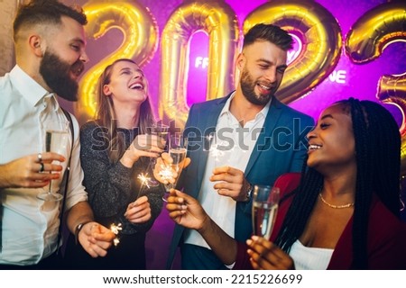 Happy multiracial friends having party in the club. Diverse people having fun while celebrating in the nightclub with champagne and sparklers. Nightlife and festive holidays concept. New Year's eve.