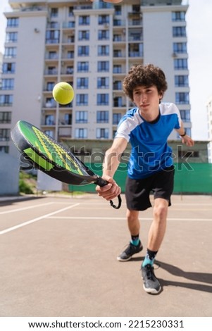 Sportive young boy with racquet playing padel in the open court outdoors Royalty-Free Stock Photo #2215230331