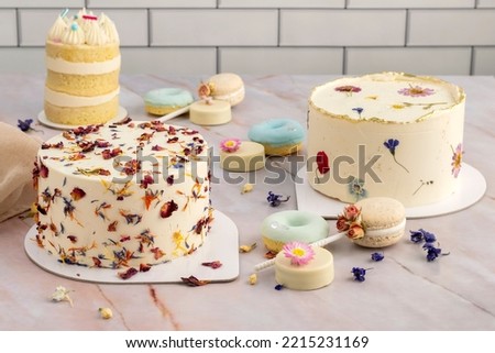 table of sweet products of fine pastry with macarons alfajores chocolate dipped cookies muffins donuts and cakes decorated with natural dry edible flowers Royalty-Free Stock Photo #2215231169