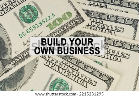 Business concept. On the dollars lies a paper plate with the inscription - Build Your Own Business