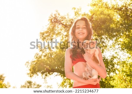 A girl and a white chihuahua. Cheerful teenage girl in a red swimsuit on vacation.