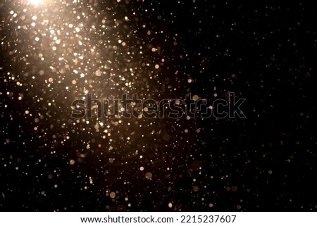 Organic dust particles floating in light ray on black background. Glittering sparkling flickering glowing. Royalty-Free Stock Photo #2215237607