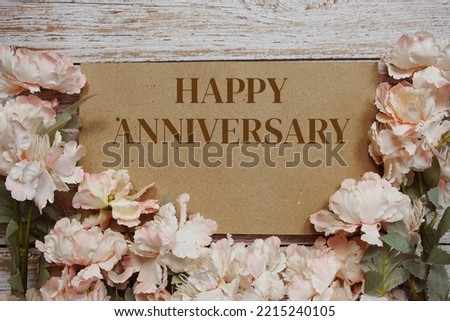 Happy Anniversary typography text with flowers frame on wooden background