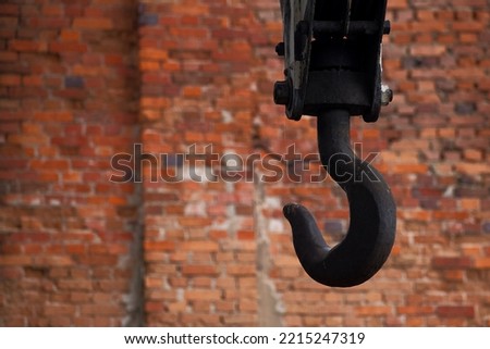 heavy metal crane hook on the brick wall background Royalty-Free Stock Photo #2215247319