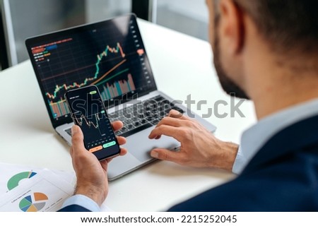 Close-up of male hands holding smartphone. Trader investor analyst using mobile phone app for cryptocurrency stock market, analyzing graph trading data index investment growth chart, plans strategy Royalty-Free Stock Photo #2215252045