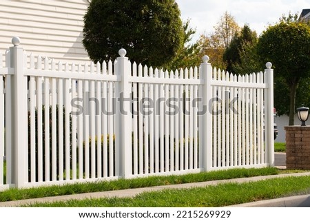 A new white vinyl fence by a grass area with trees behind it green property modern Royalty-Free Stock Photo #2215269929