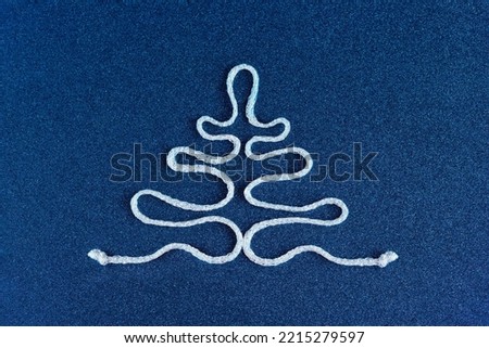 Stylish silver rope Christmas tree on a shiny blue background.ribbon Christmas tree. 