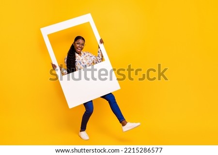 Full length body size view of attractive cheerful girl dancing with paper frame isolated over bright yellow color background