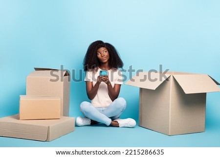 Full length portrait of minded person sitting floor hold telephone look empty space isolated on blue color background