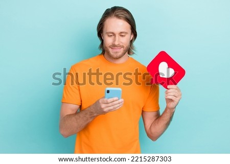 Photo of good mood man dressed orange t-shirt chatting modern gadget holding feedback card isolated turquoise color background