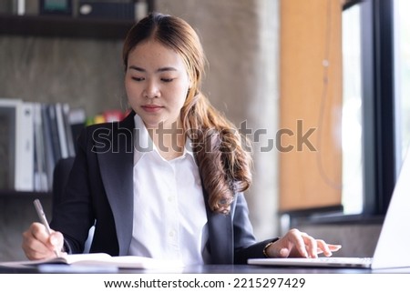 Asian business woman working on laptop and taking notes at the office
