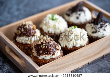 Cupcakes and muffins placed in wooden box. Chocolate and creme with nuts. Fresh home make baked sweets.