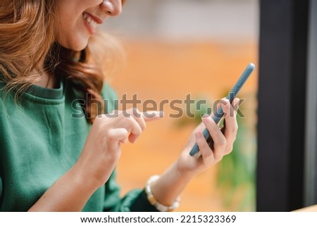 Portrait of an Asian woman holding a smartphone, typing messages, chatting with friends. on social networks mobile application concept Shopping online, browsing the web, ordering food Royalty-Free Stock Photo #2215323369