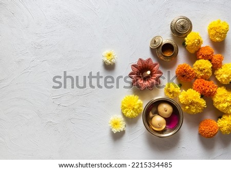 Marigold flowers scattered on white background with Indian traditional lamp, kumkum and sweet. Beautiful Hindu festive background or photo. View from above.