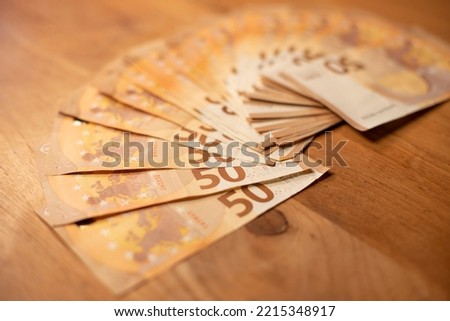 wad of cash lying on a wooden table. Banknotes of 5O euros. Image that can be used as background or page background. Capitalism and finance concept.
