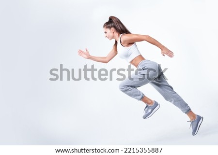 Sports woman runner on a white background. Photo of an attractive woman in fashionable sportswear. Dynamic movement. Side view. Sports and healthy lifestyle. Mixed media
