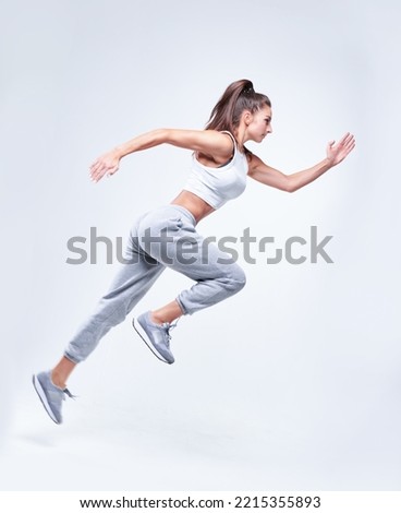 Sports woman runner on a white background. Photo of an attractive woman in fashionable sportswear. Dynamic movement. Side view. Sports and healthy lifestyle. Mixed media Royalty-Free Stock Photo #2215355893