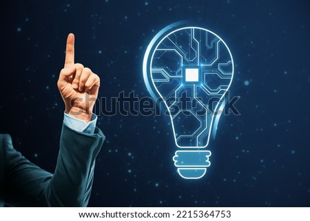 Close up of businessman hand pointing up with abstract glowing light bulb with chip hologram on blurry dark background. Artificial intelligence and neural network concept