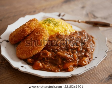 Omelette rice topped with curry and croquettes