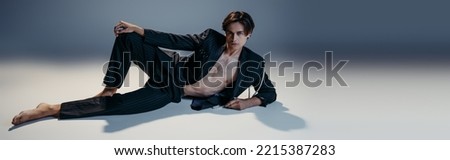 stylish man in suit with pearls and hairy chest posing on dark grey background, banner