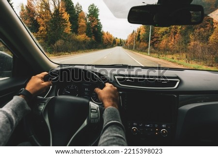 Man driving car on the country road in autumn. Rear view Royalty-Free Stock Photo #2215398023