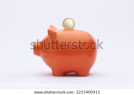 an orange piggy bank with a coin in the form of a deposit Royalty-Free Stock Photo #2215400411