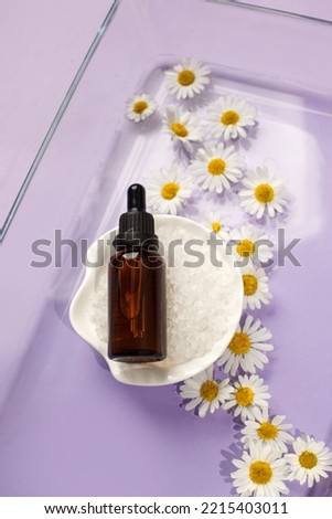 Cosmetic skin care serum dropper and bottle with chamomile flowers on light very peri background, water splash with copyspace, banner for spa salon, cosmetology, aromatherapy, organic care