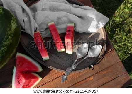 Tasty ripe watermelons and spoons on wooden table outdoors, flat lay