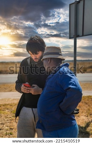 African and Caucasian men talking and using a smartphone on the road