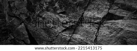Black white rock texture with cracks. Rough mountain surface. Close-up. Dark grey. Stone granite background with space for design. Banner. Wide. Long. Panoramic.