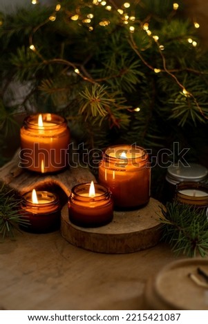 Soy candles burn in glass jars. Comfort at home. Candle in a brown jar. Scent and light. Scented handmade candle. Aroma therapy. Christmas tree and winter mood. Cozy home decor. Festive decoration. Royalty-Free Stock Photo #2215421087