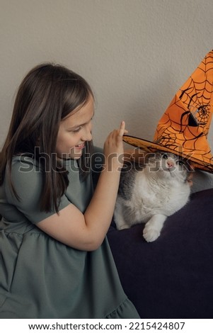 Girl with cat in orange hat, halloween concept