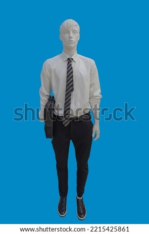 Full length image of a male display mannequin wearing white shirt, tie with stripes and black trousers, carrying a briefcase isolated on a blue background