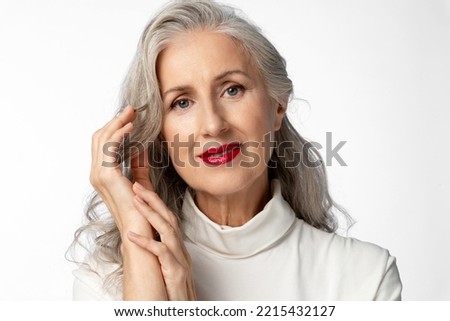 A beautiful stylish and elegant older lady with a smile. Portrait of a beautiful elderly woman with loose gray hair on a white background. Royalty-Free Stock Photo #2215432127