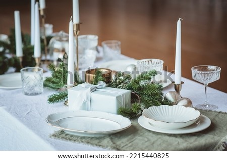 Christmas tablecloth with candles, plates, plants and presents. Focus is at toys. Holiday concept Royalty-Free Stock Photo #2215440825