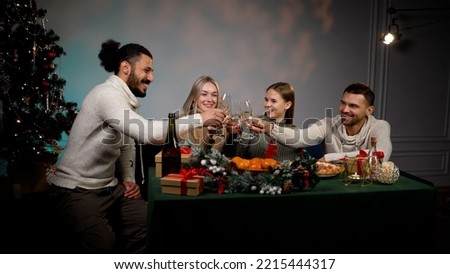 Friends raise glasses of champagne for the New Year. To your health People are celebrating and raising their glasses for toasts. A group of four multiethnic friends enjoying a house party.