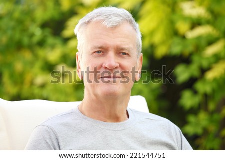 Portrait of modern grandfather sitting at garden at home. 