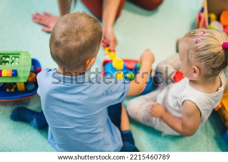 little children playing with toys in the nursery, indoor kindergarten concept. High quality photo Royalty-Free Stock Photo #2215460789