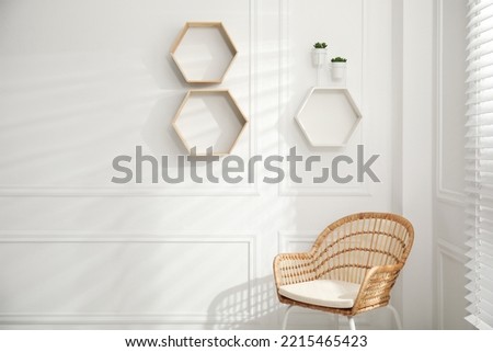 Honeycomb shaped shelves with plants on white wall indoors