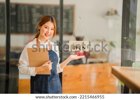 Young Asian female employee standing in front of the shop with a sign opening a food and beverage concept.