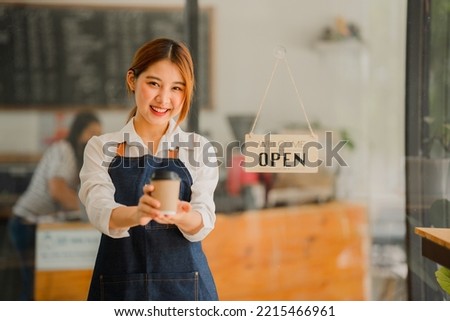 Young Asian female employee standing in front of the shop with a sign opening a food and beverage concept.