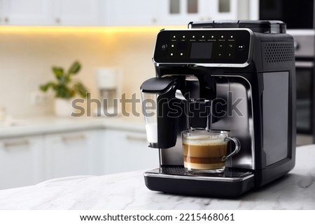 Modern coffee machine with glass cup of latte on white marble countertop in kitchen Royalty-Free Stock Photo #2215468061