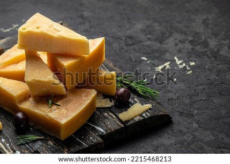 Parmesan cheese on a wooden board, Hard cheese on a dark background. banner, menu, recipe place for text, top view. Royalty-Free Stock Photo #2215468213