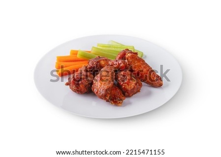 Fried chicken wings with celery and carrots in a plate on a board on a white background