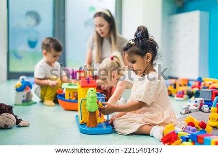preschoolers building with toys and cubes and enjoying in kindergarten with teacher, creative activities for kids. High quality photo