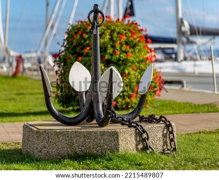 Symbol photo shipping - exhibited old drag anchor in foreground with blurred sailing yachts in background