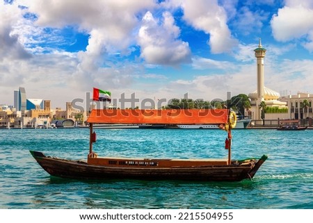 Abra - old traditional wooden boat and Al Farooq Mosque on the bay Creek in Dubai, United Arab Emirates Royalty-Free Stock Photo #2215504955