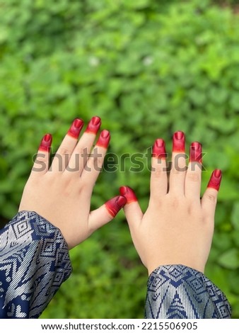 Red henna on fingernails with green background