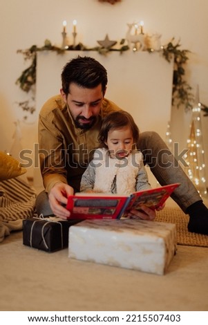 Young happy family reading fairy tales while relaxing at home during Christmas holidays.